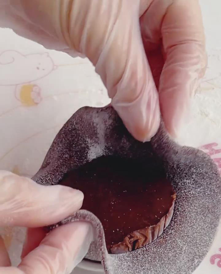 Take one portion of the frozen chocolate ganache and place it in the center of the dough