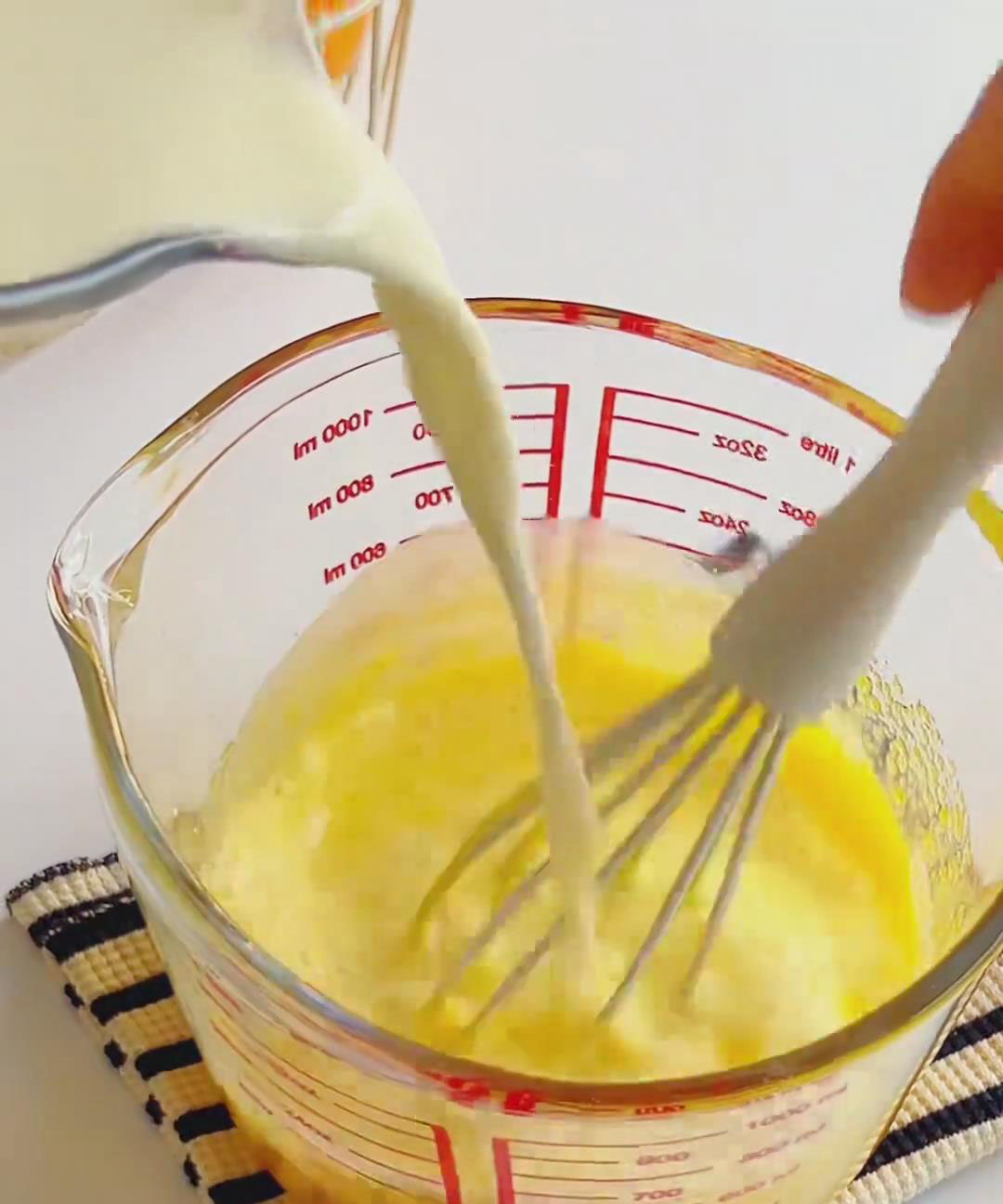 Slowly pour the cooled milk into the egg yolks