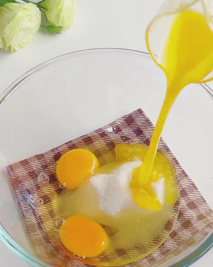 In a large mixing bowl, combine the 2 room temperature eggs, 65g of fine granulated sugar, 2g of salt, and the cooled, melted butter